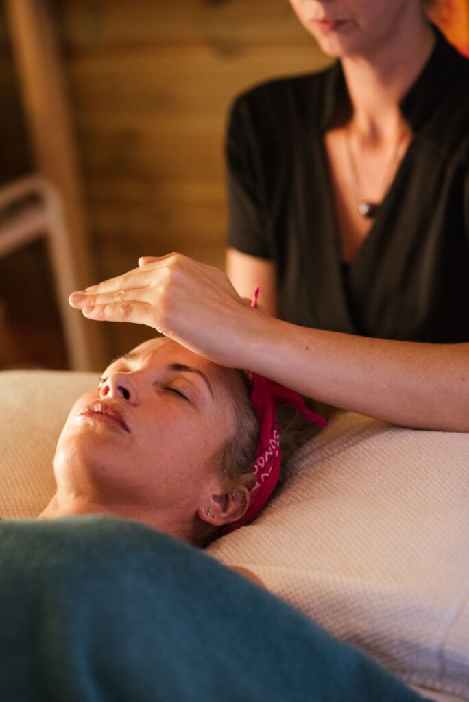 Personne allongée et détendue pendant une séance de reiki, le praticien posant doucement les mains